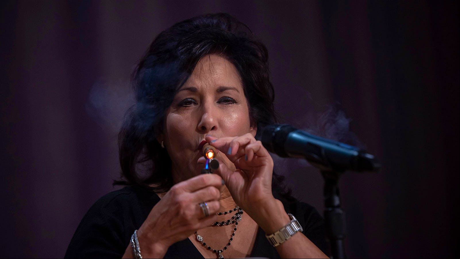 Cynthia Fuente-Suarez, lighting an Arturo Fuente Hemingway Between the Lines on stage.